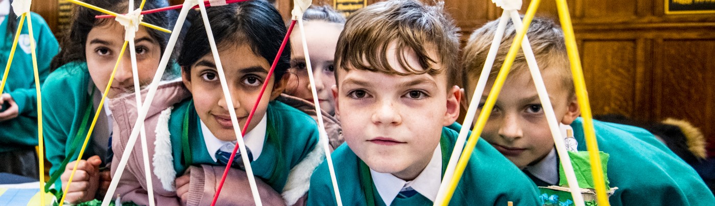 Row of school children in uniform doing science experiments 