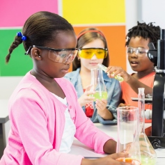 Children in safety goggles playing witch scientific equipment