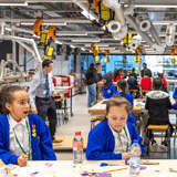 Children sitting at a bench in an engineering workshop